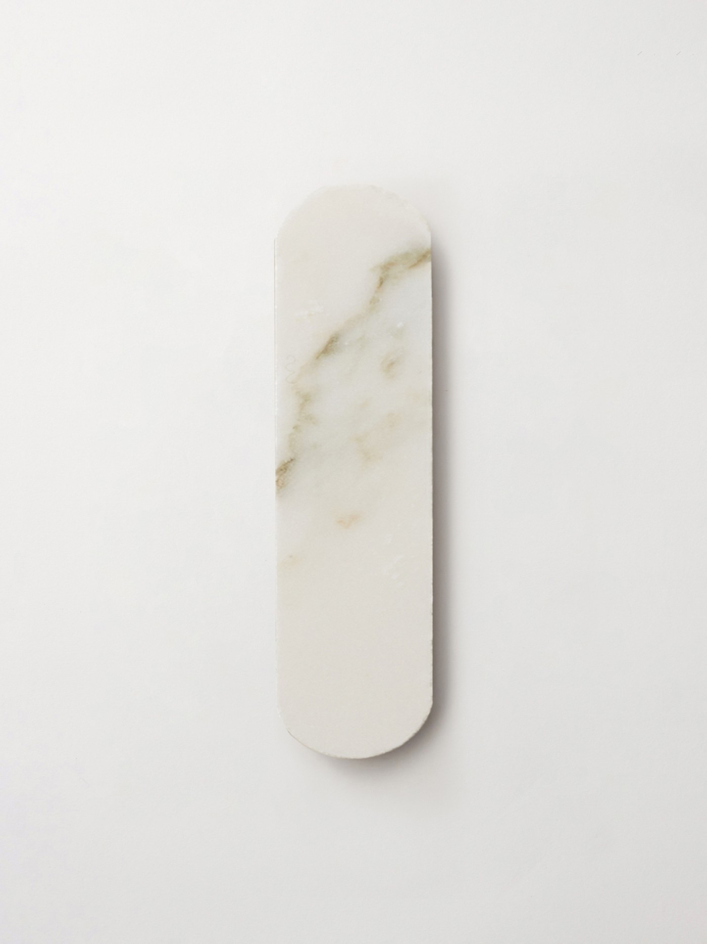 an oval piece of marble tile on a white surface.