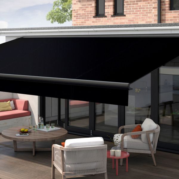 Black retractable cassette awning, fully extended and angled, shading a patio; covers glass sliding doors above wood decking, with outdoor seating, low table, and daytime soft natural light.