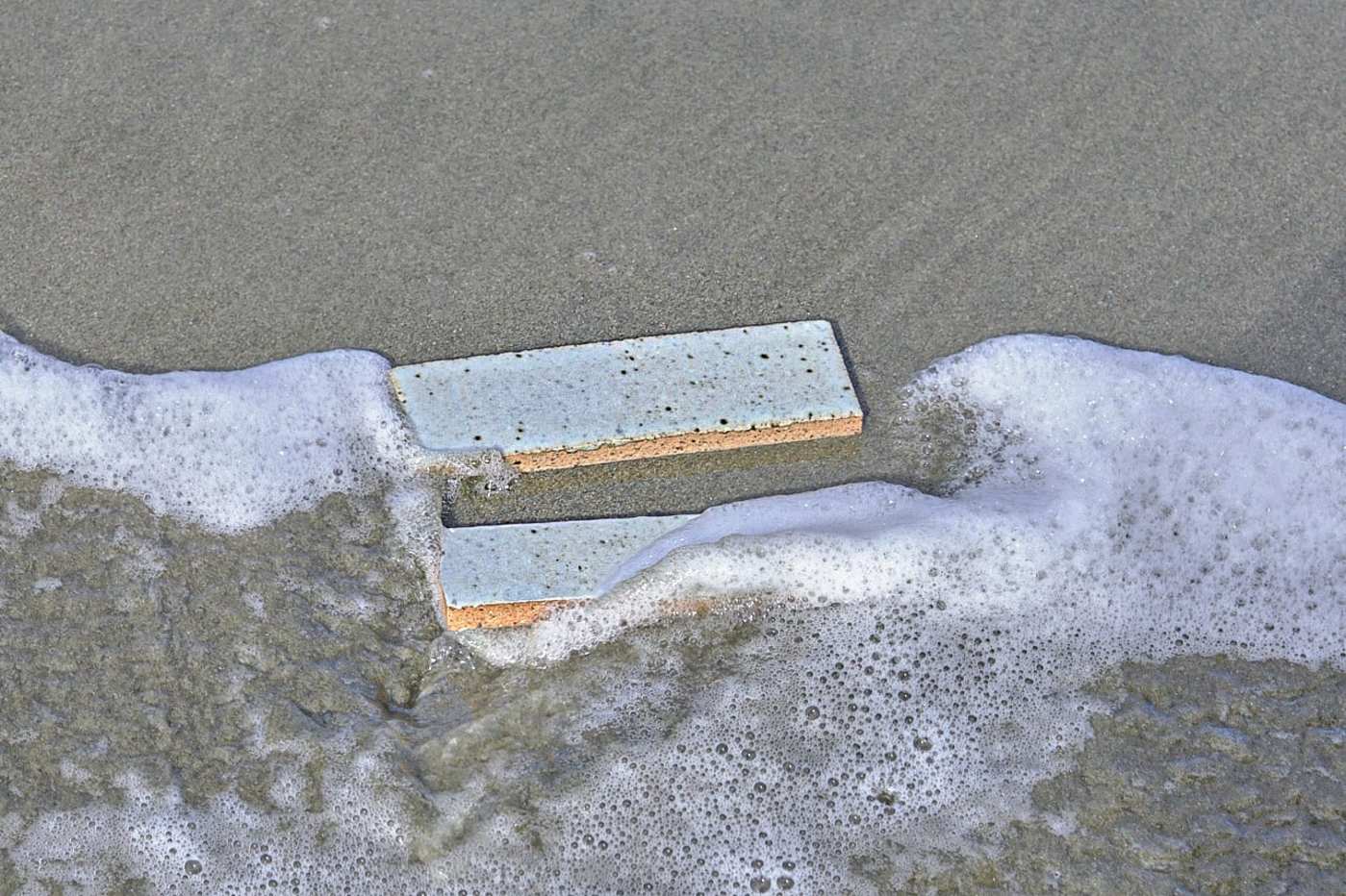 a pair of white rectangle tiles in the sand.