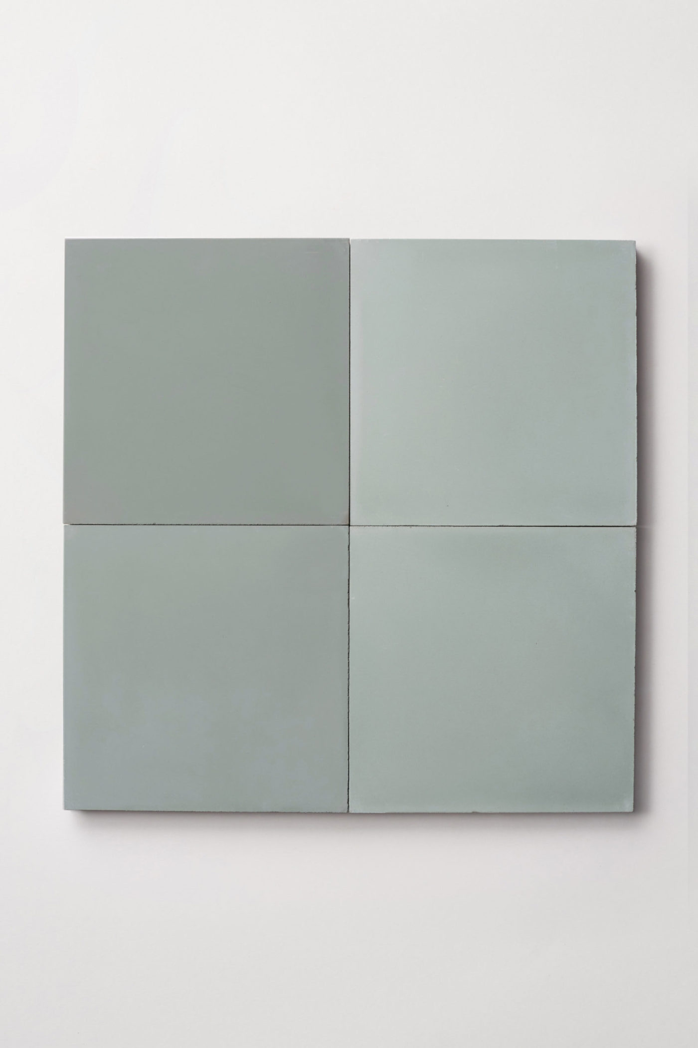 four light green square tiles on a white surface.