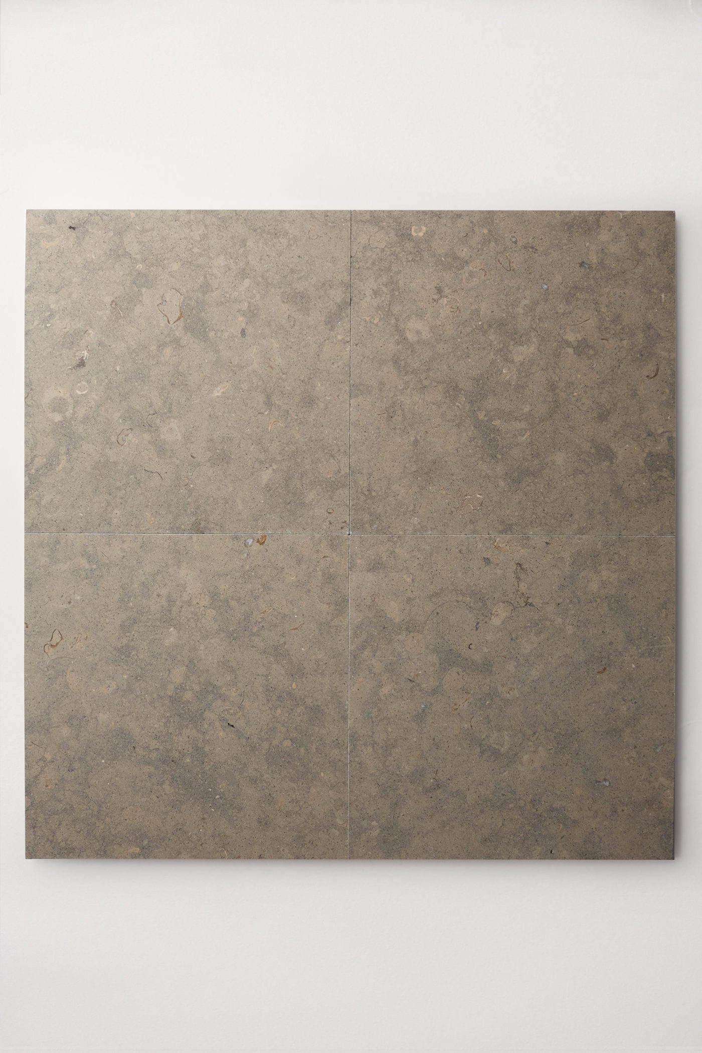 four square grey limestone tiles on a white surface.