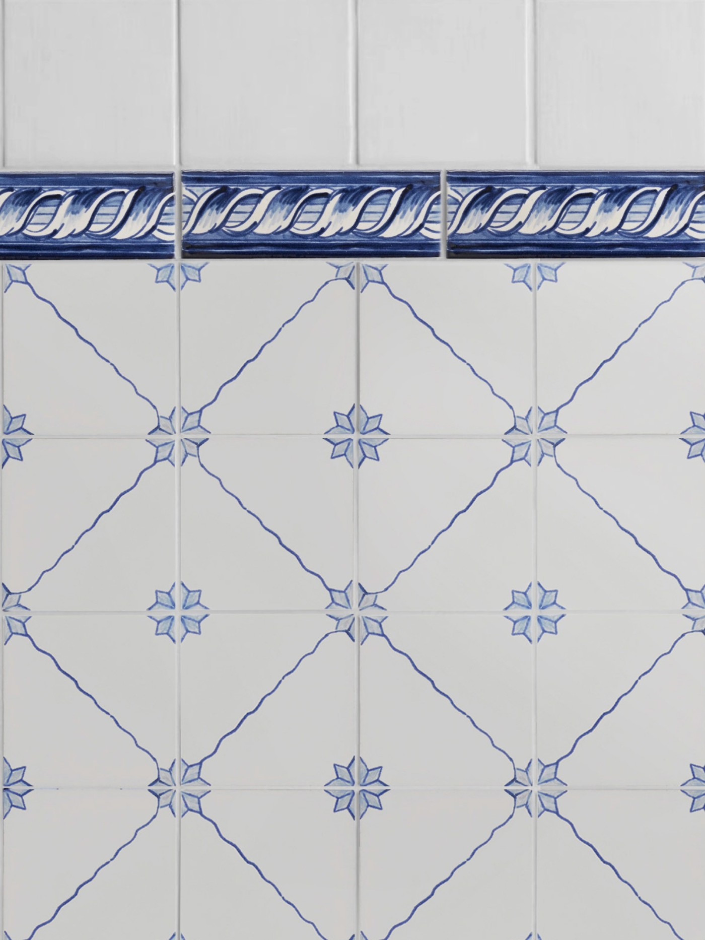 a blue and white tiled wall with a decorative border.