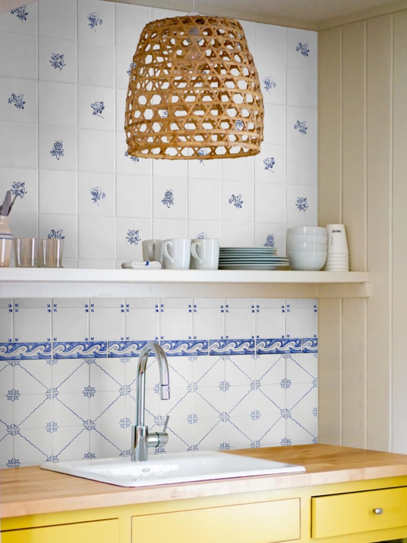 a blue and white tiled kitchen backsplash with yellow cabinets.