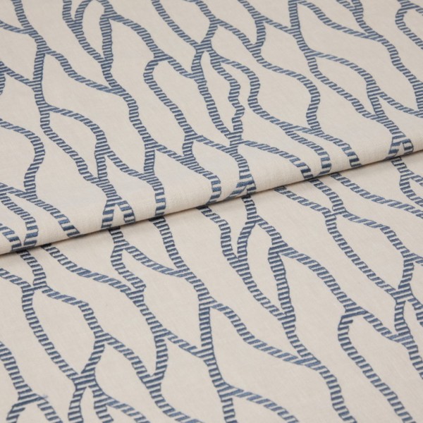 Beige fabric with repeating blue rope-like chain pattern, folded and layered across itself; close-up on a flat surface with soft, even lighting that emphasizes the woven texture.