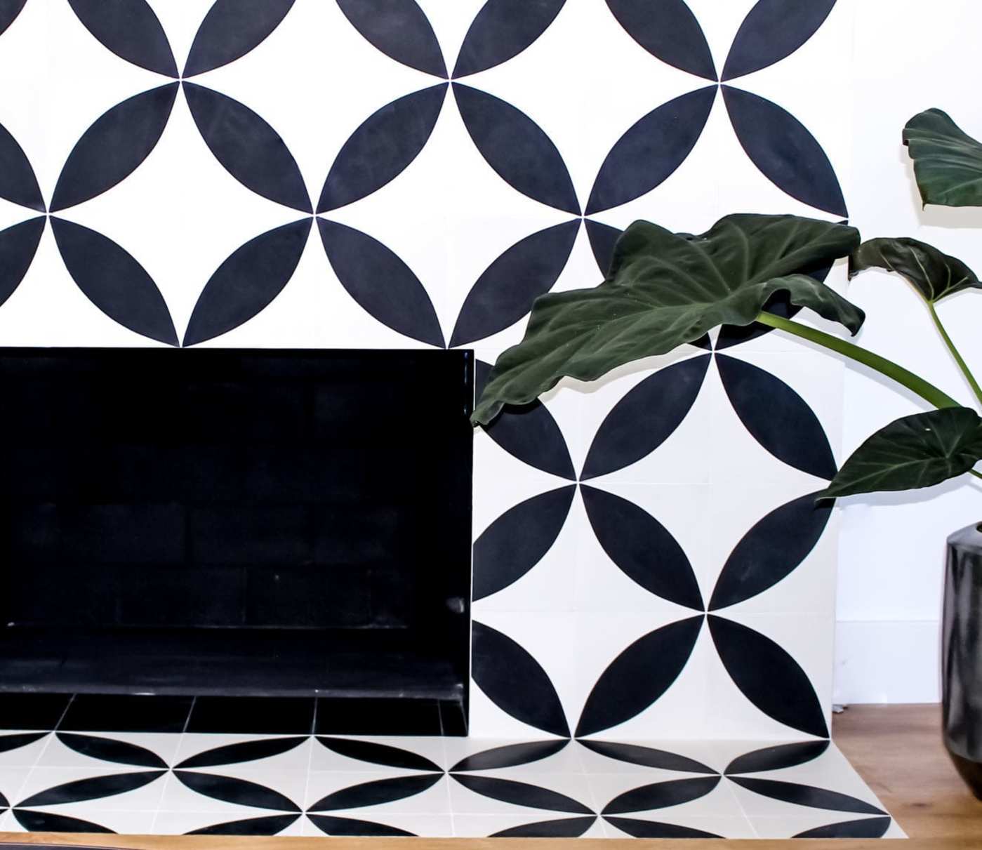 a black and white tiled fireplace with a potted plant.