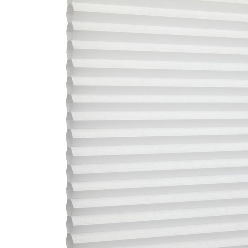White honeycomb (cellular) blind with horizontal pleats, closed and softly diffusing daylight; minimal, bright interior with no visible furniture or view.