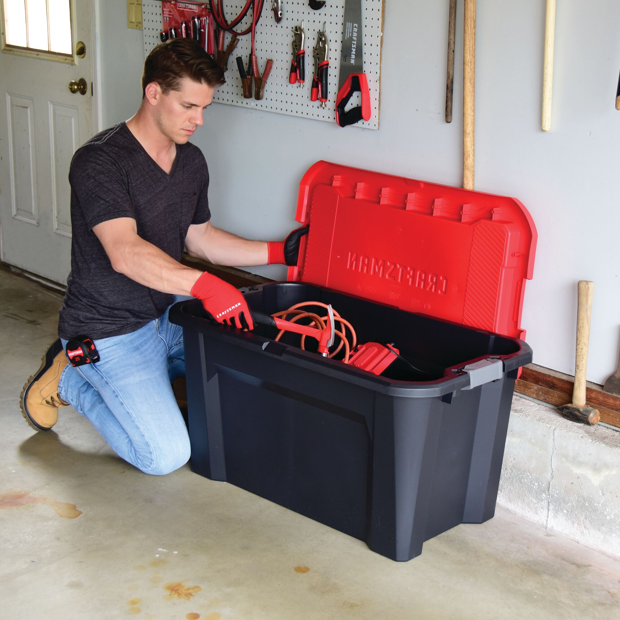 40 Gallon latching tote being used by a person to store tools.