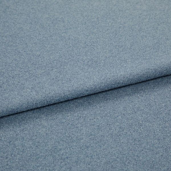 Light blue woven fabric (denim-like) folded once, forming a diagonal layered edge; close-up view showing fine texture and even studio lighting on a plain surface.