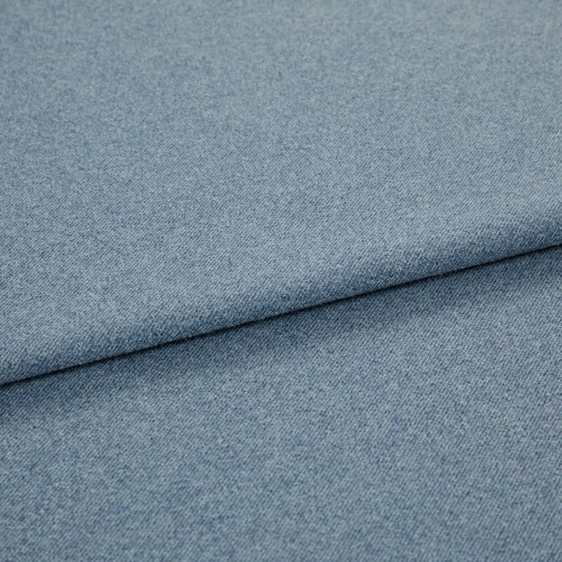 Light blue woven fabric (denim-like) folded once, forming a diagonal layered edge; close-up view showing fine texture and even studio lighting on a plain surface.