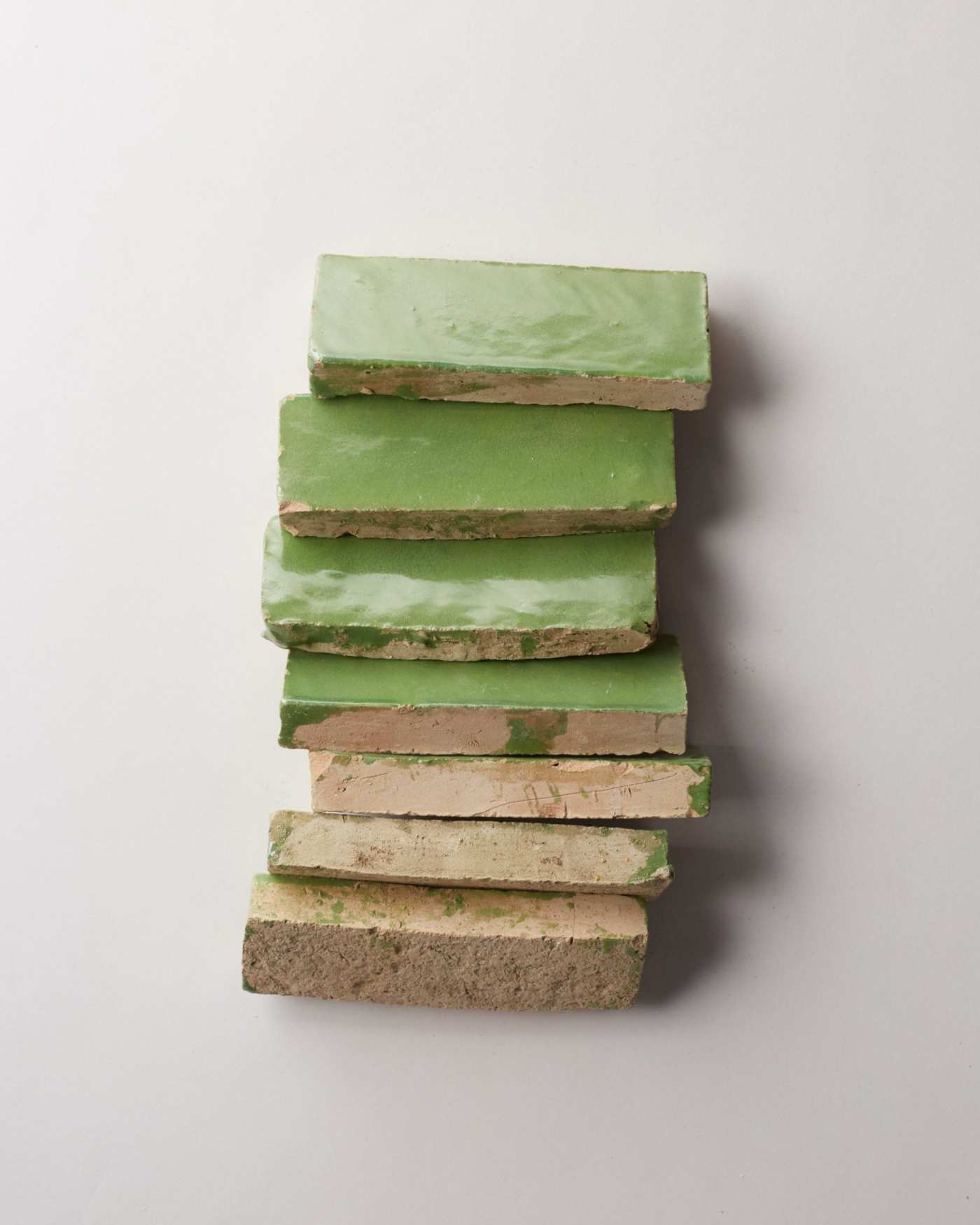 a stack of green tiles on a white surface.