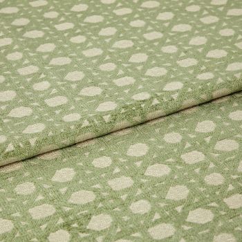 Green patterned woven fabric with raised geometric dots and lattice, folded over itself and showing textured pile; close-up studio view with soft, even lighting emphasizing the fibers.