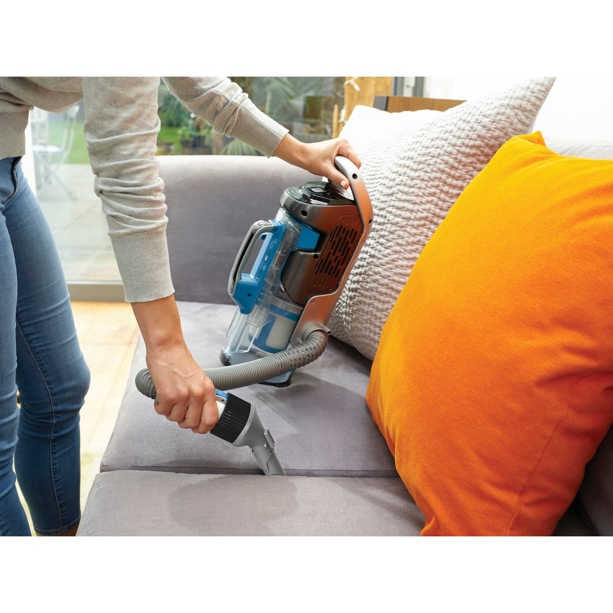 Person using handheld feature of BLACK+DECKER cordless vacuum on sofa