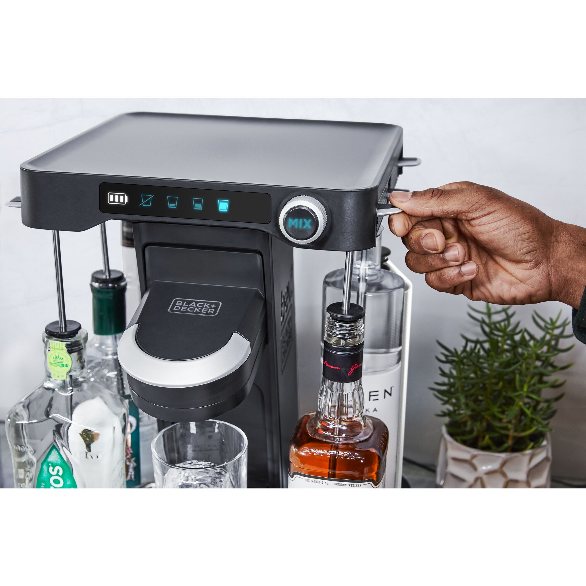 close-up, in the kitchen, of a man's hand loading a bottle of whiskey into the easy load liquor system on the bev by BLACK+DECKER™ cocktail maker