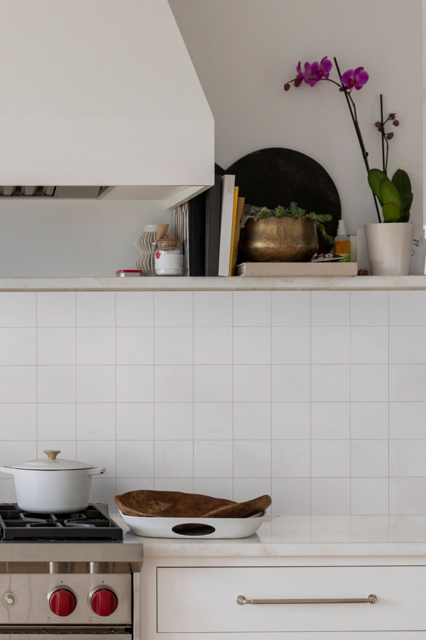 a white kitchen with a stove and pots on the counter.