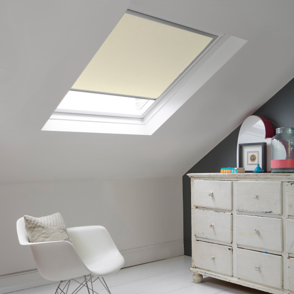 Room with white eaves wall, dark blue-grey wall to right with a shabby chic white drawer unit, a contemporary white chair, white painted floorboards and a skylight blind in almond.