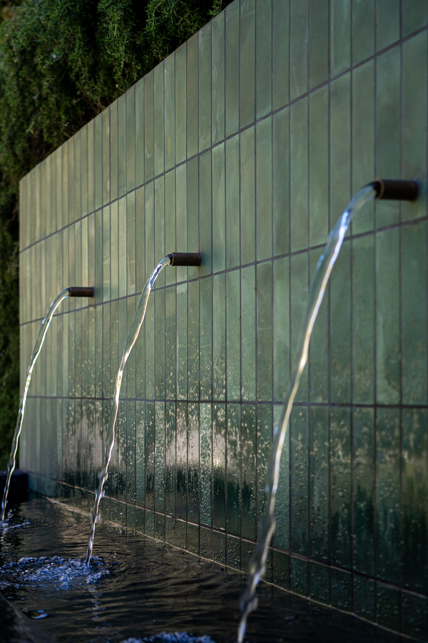 a green tile wall with a water fountain.