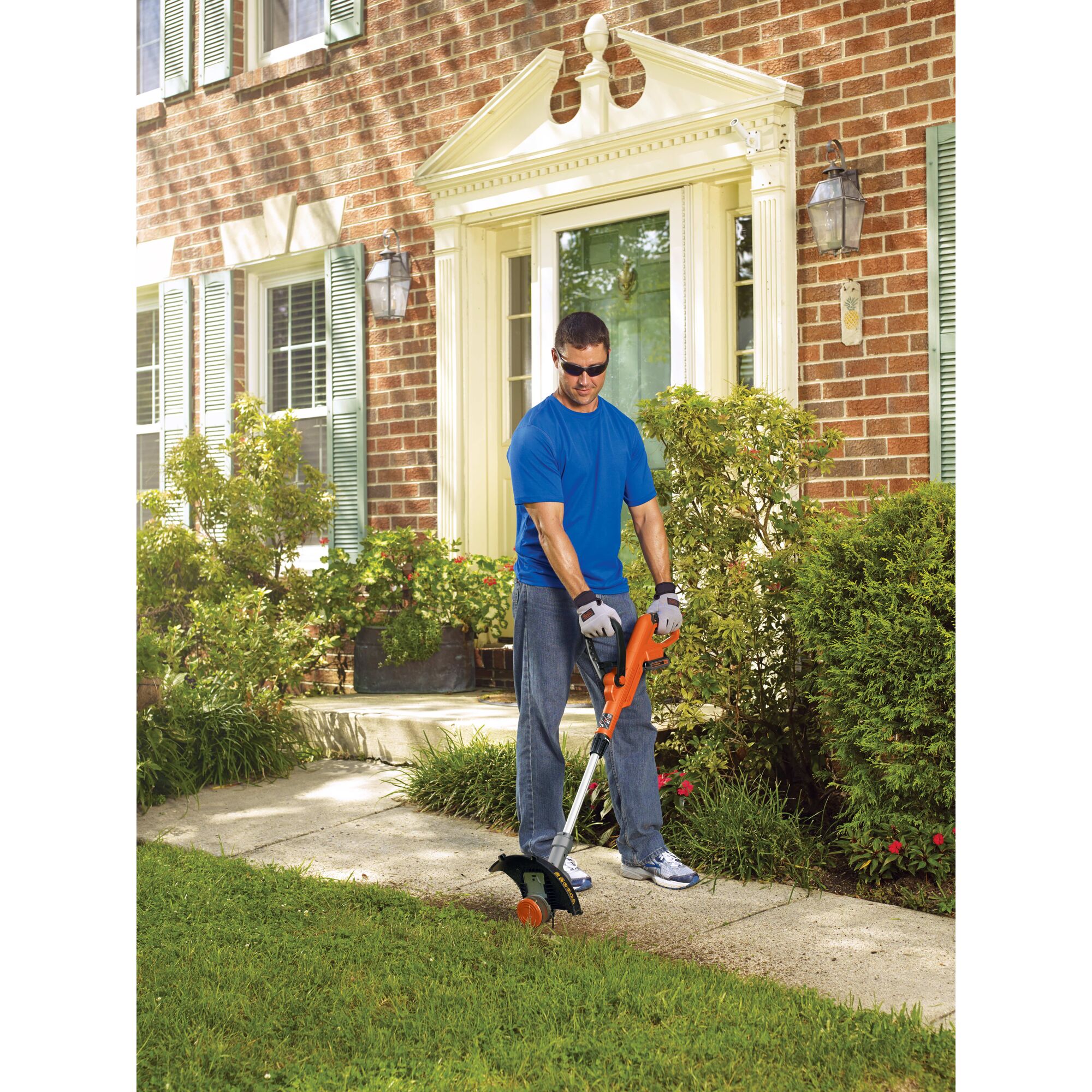 Man using 20V Max Lithium String Trimmer 12In. along the path to the front door of a house.