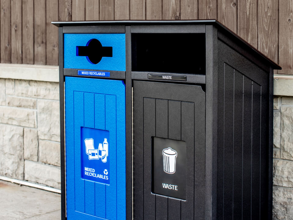 black and blue recycled plastic recycling and waste container showing effective signs and labels outside against a building