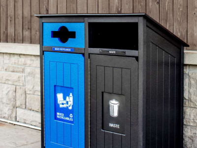 black and blue recycled plastic recycling and waste container showing effective signs and labels outside against a building