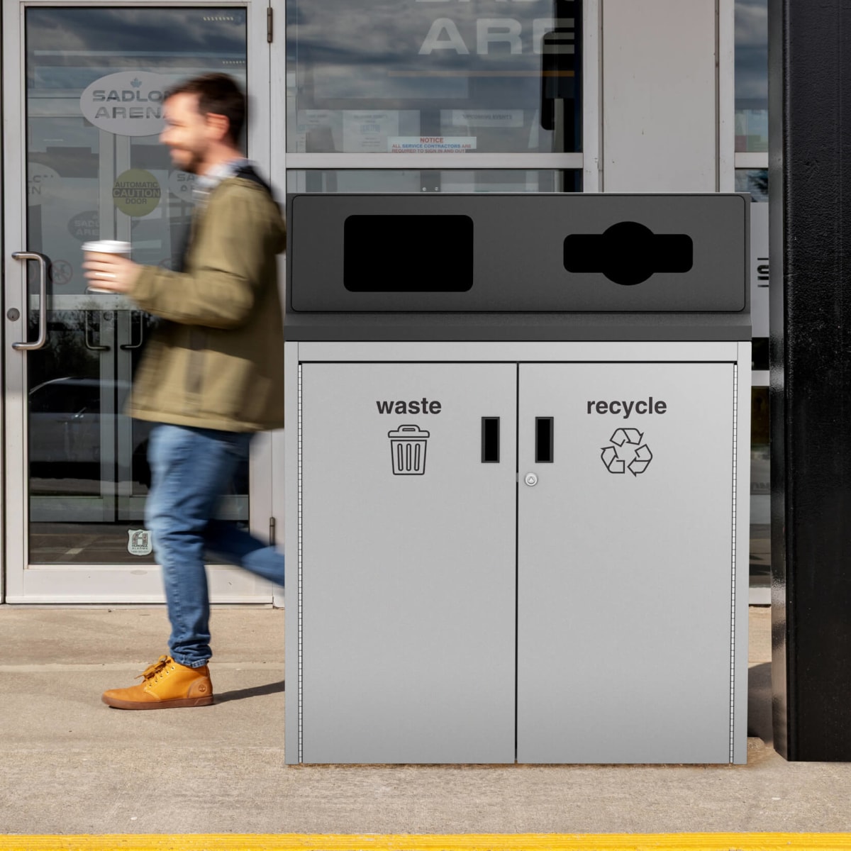 metal waste and recycling bin at a hockey arena with a man walking holding a coffee