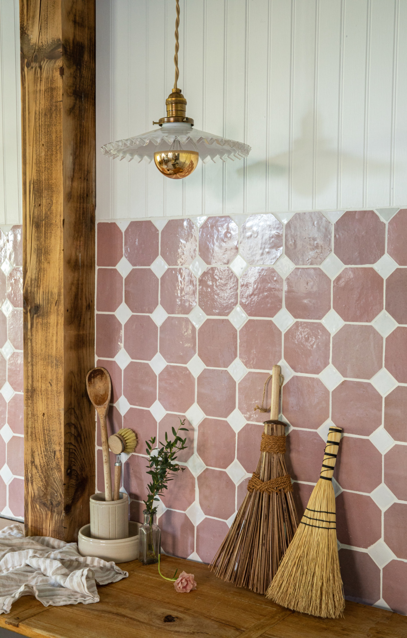 a kitchen with a pink tiled wall and a broom.