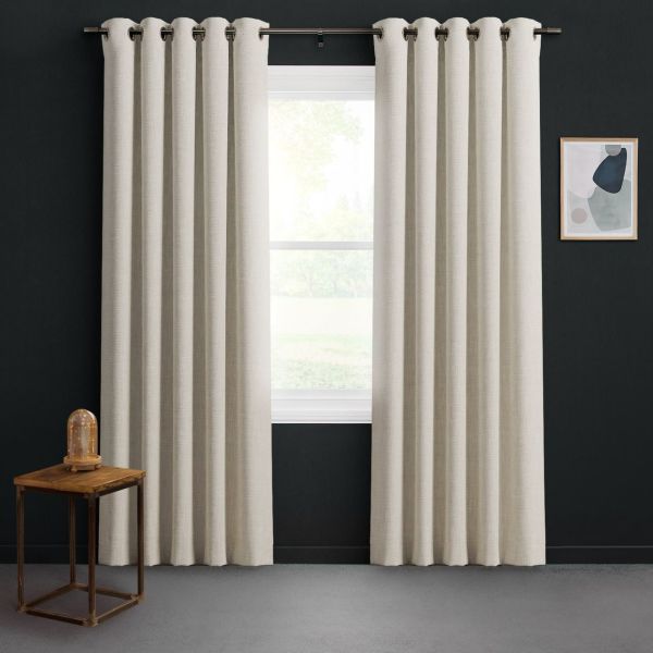 Beige grommet-top curtains, full-length textured panels hung on a metal rod, parted to reveal a sunlit window; dark charcoal-walled room with small wooden side table and abstract wall art.