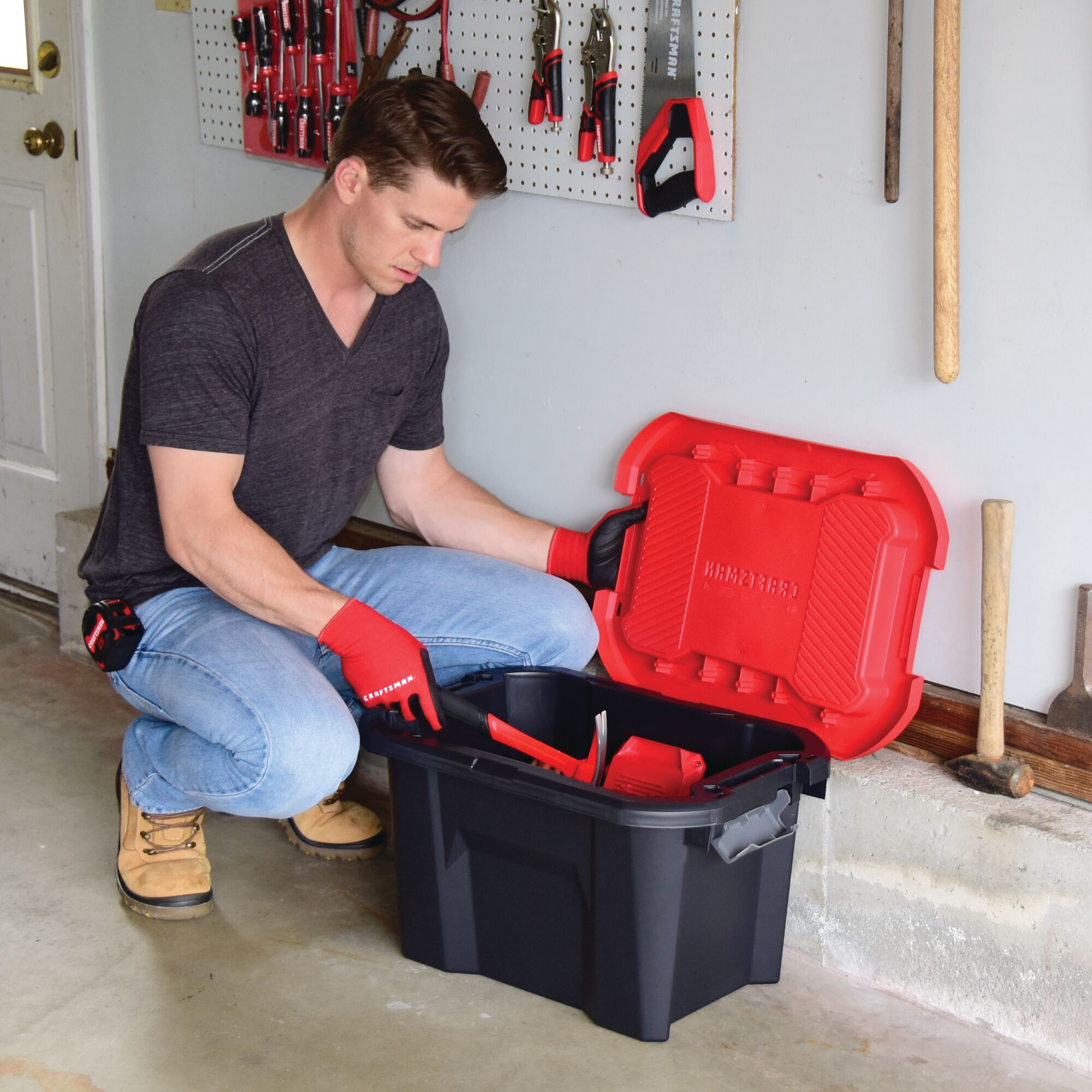 10 Gallon latching tote being used by a person to store tools.