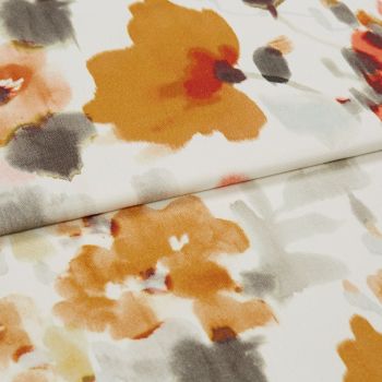 Folded white fabric with large watercolor-style orange, gray, and red floral prints, lying flat and slightly creased, shown in close-up under soft neutral studio lighting.