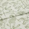 Folded curtain fabric with green line-drawn botanical print; overlapping fold reveals large floral and bud motifs, laid flat in a close-up studio view with soft, neutral lighting.