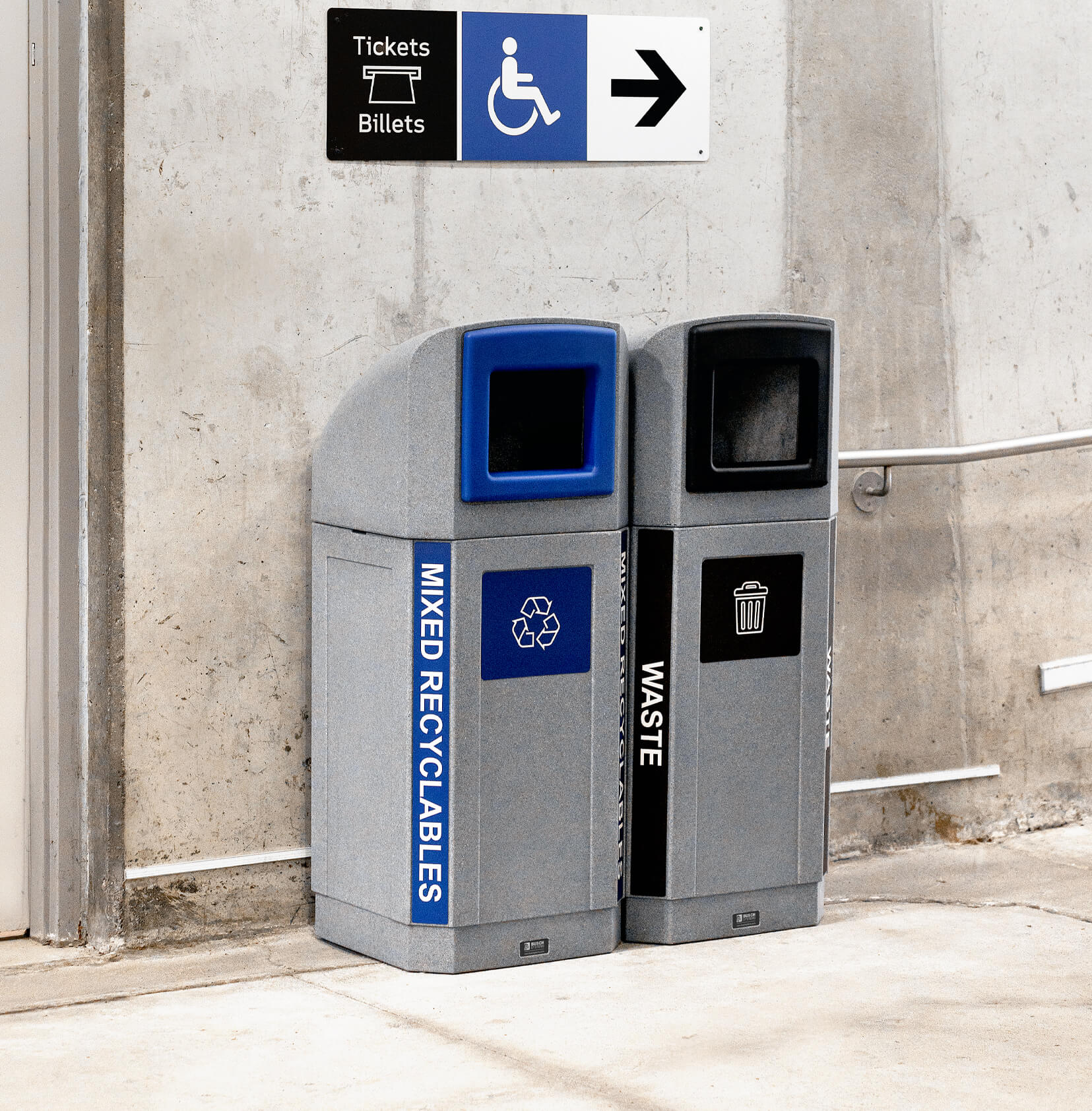 double grey plastic waste and recycling containers with canopy lids and color coded trim openings and body labels in a subway station