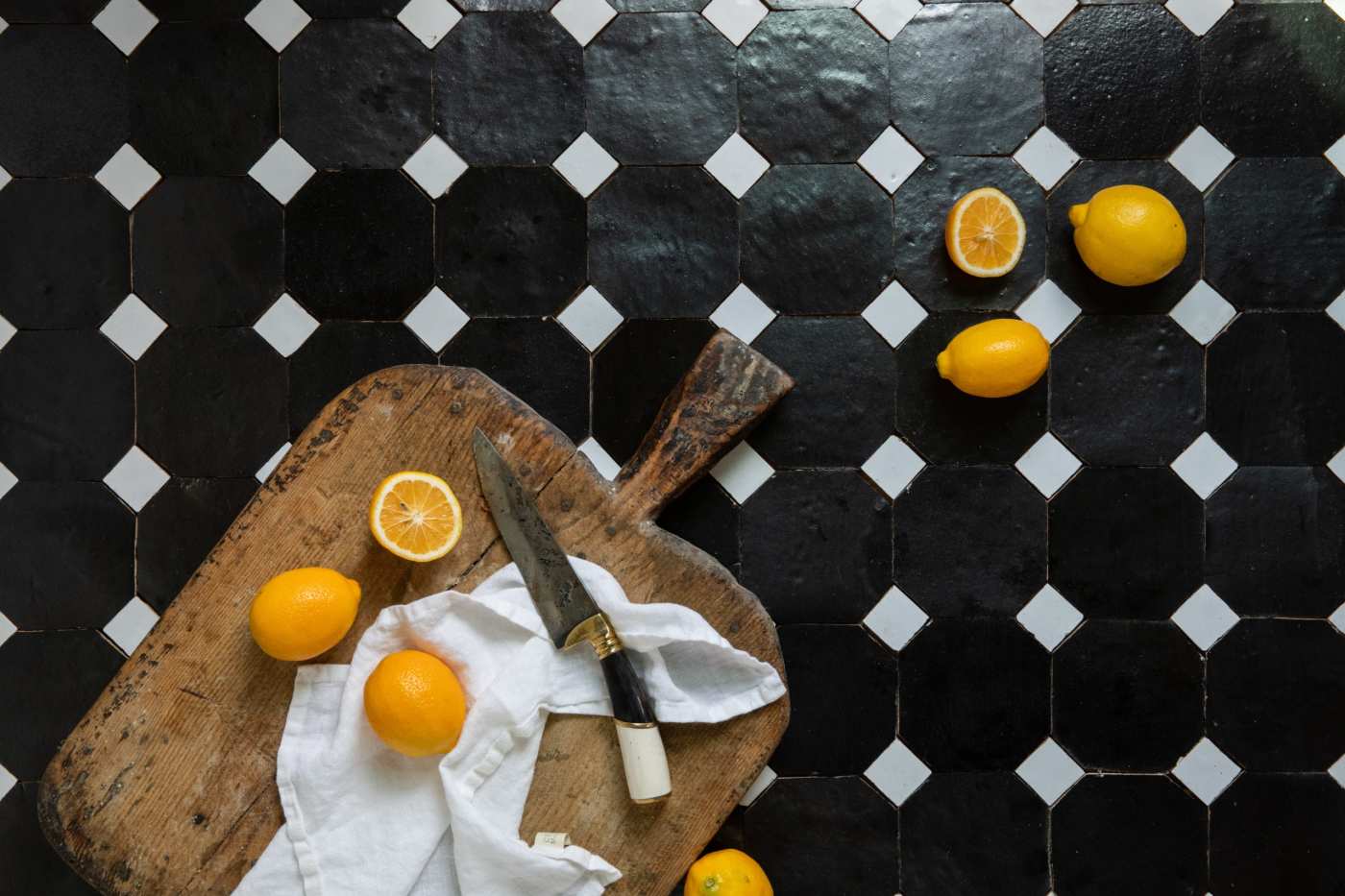 a black tiled counter with lemons and a cutting board.