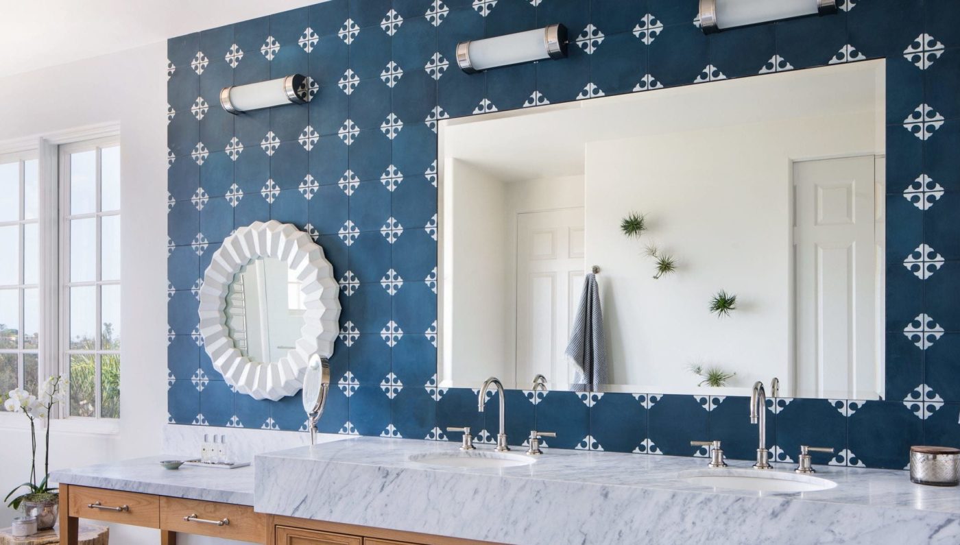 a bathroom with a blue and white tile sink backsplash and marble counter tops.