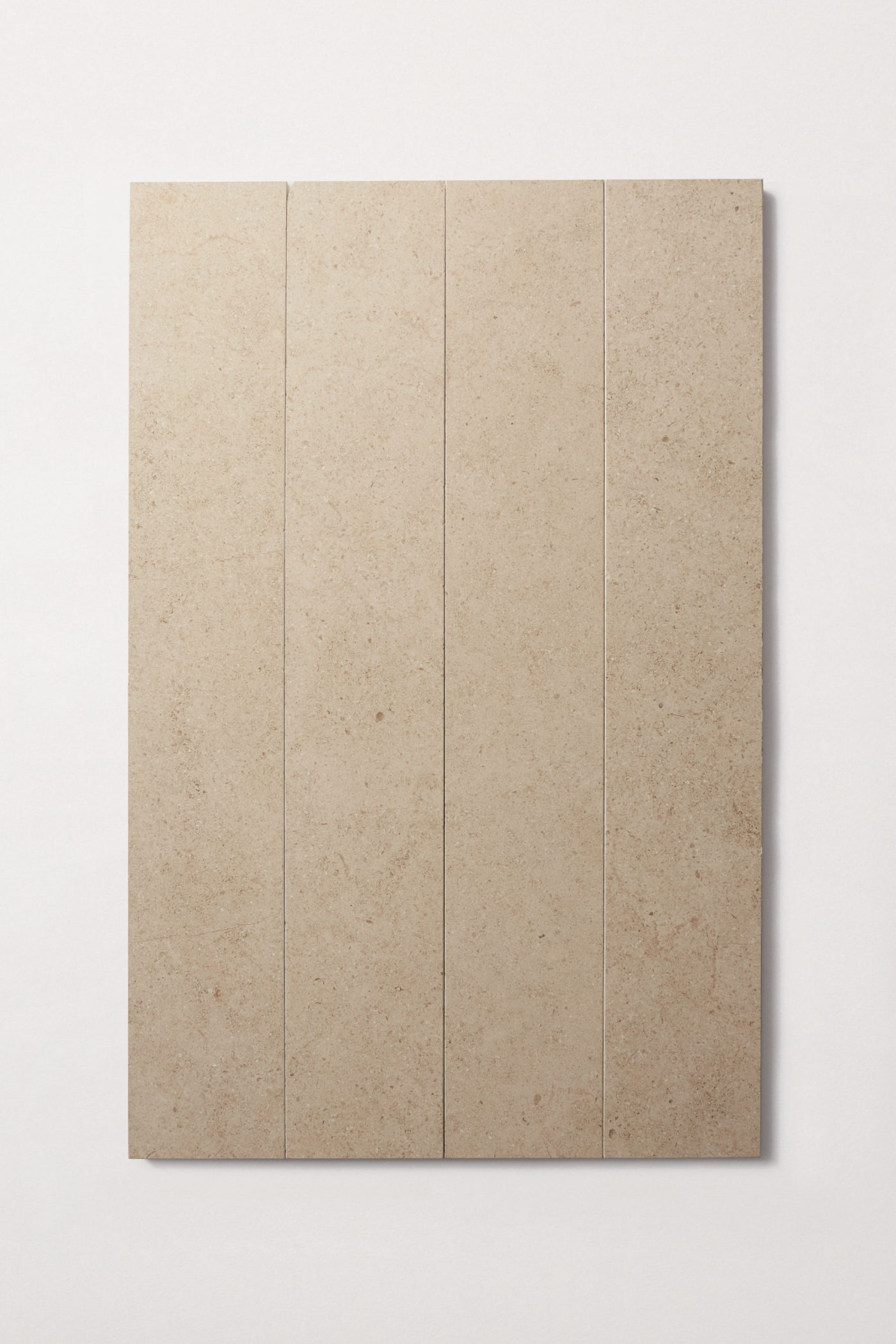 four beige limestone tiles on a white surface.