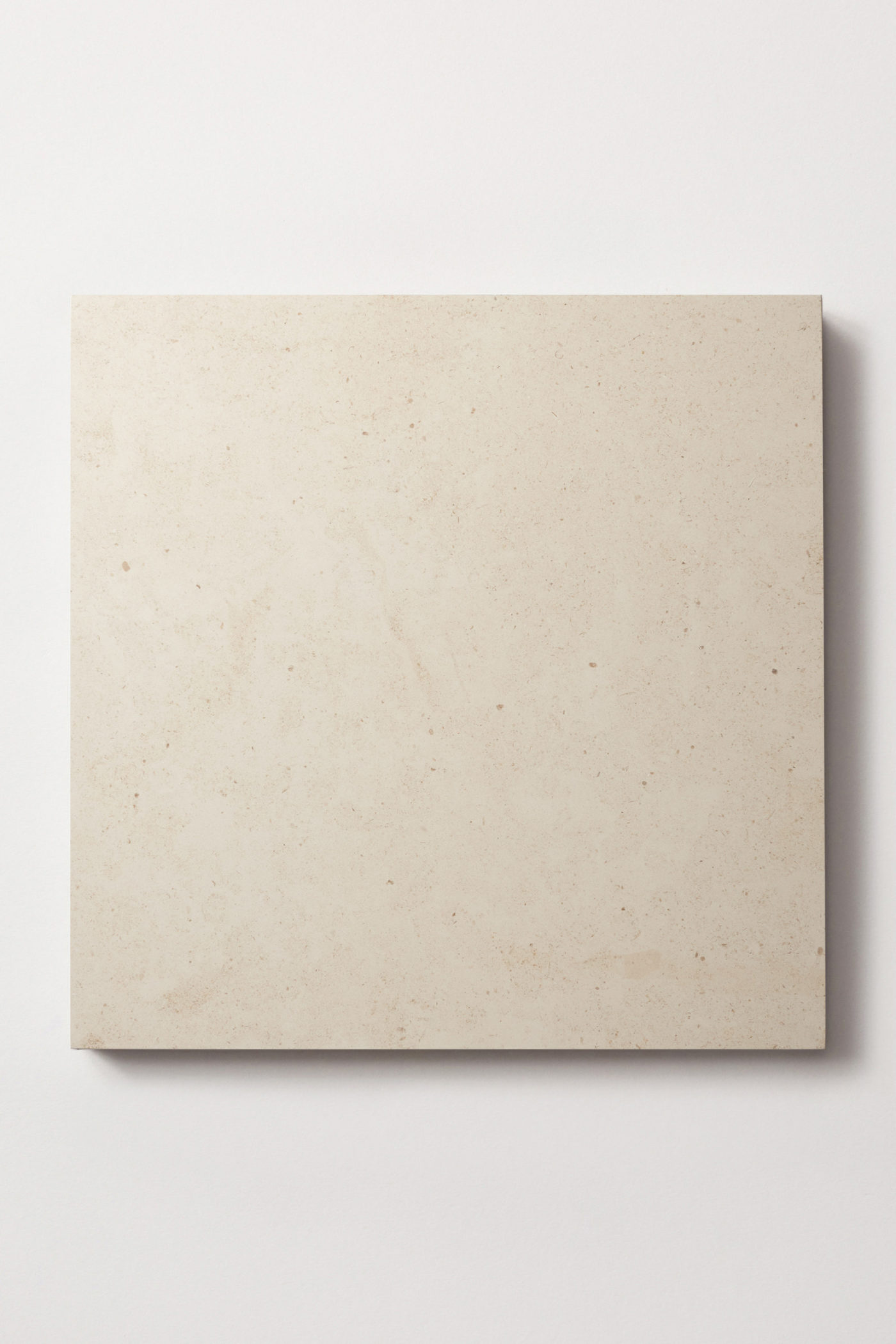 a beige limestone square on a white surface.