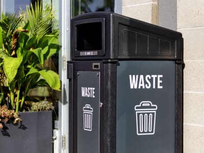 black recycled plastic waste container with sloped canopy lid and large body signs for improved waste diversion