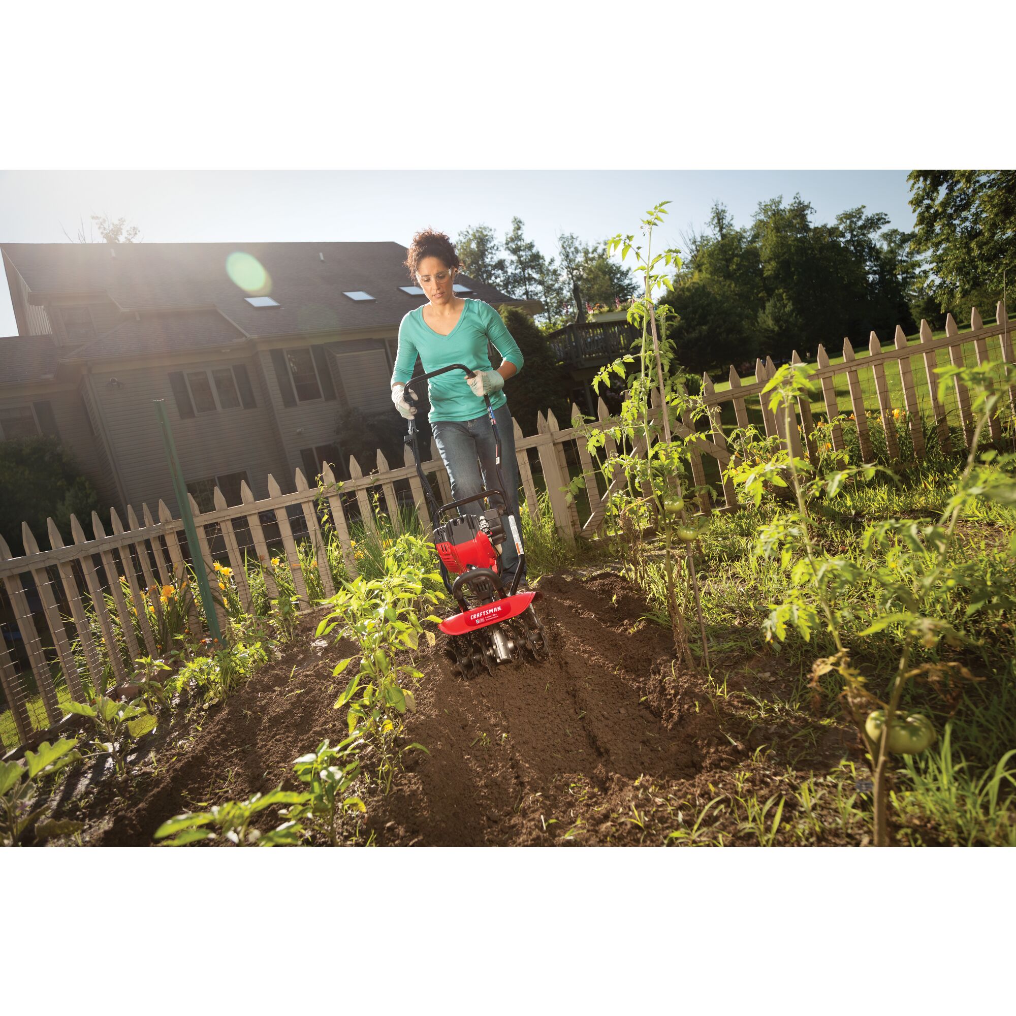CRAFTSMAN gas cultivator in front view cultivating garden in jeans and teal shirt