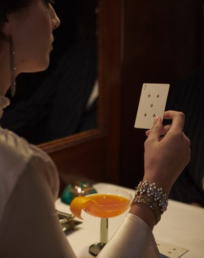 a woman holding a playing card in front of a mirror.