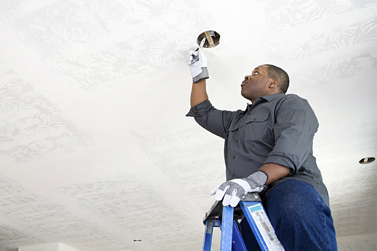 Man on ladder cutting round ceiling hole