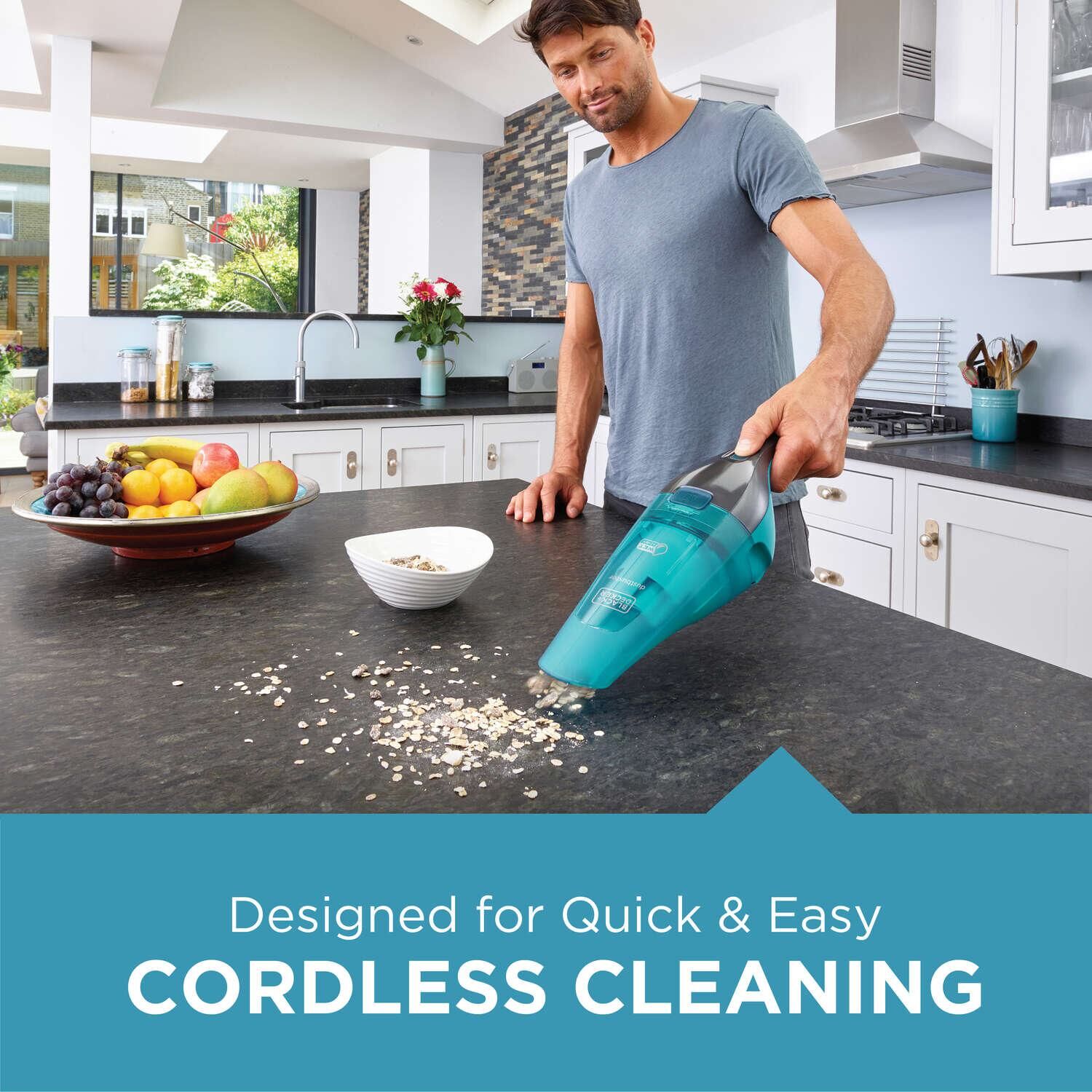 dust buster Quick Clean Cordless Hand Vacuum wet Dry being used by person to clean pieces of food from kitchen shelf.