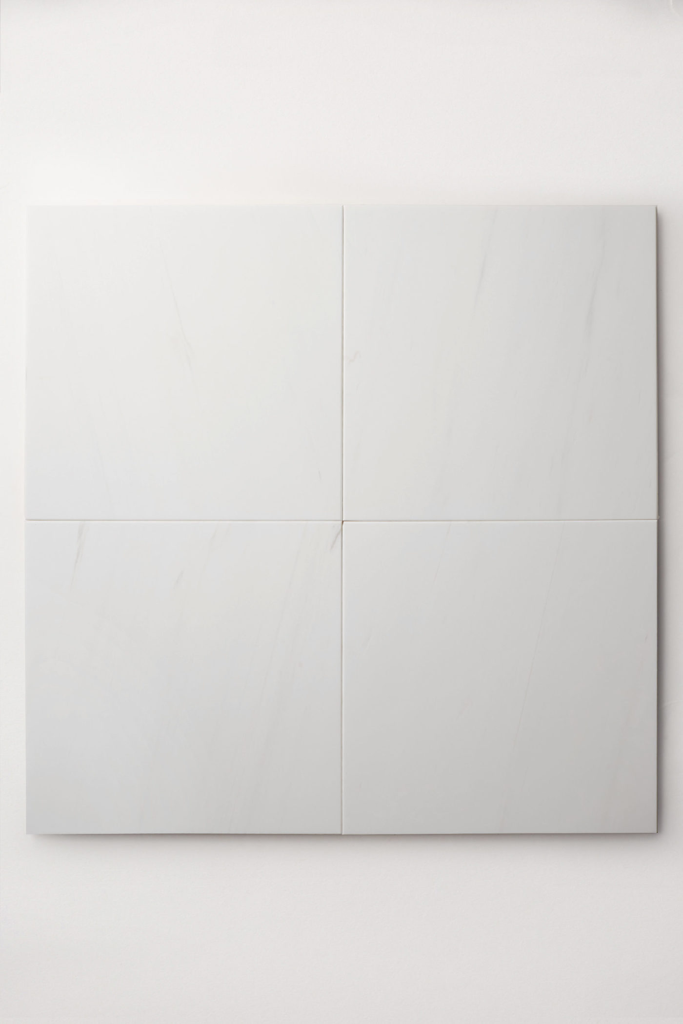 four white square tiles on a white surface.