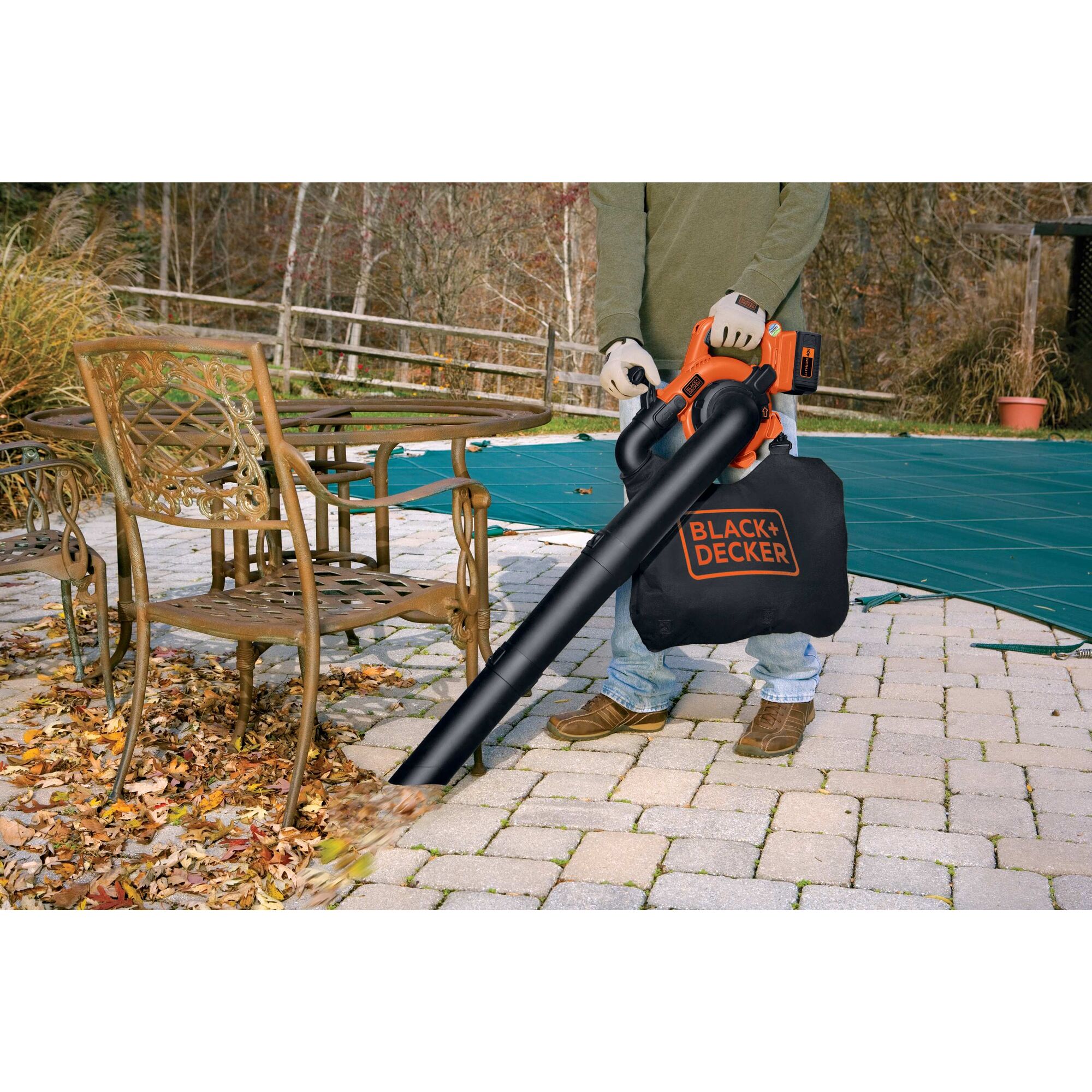 Man using Cordless Leaf Blower/Vacuum to clear leaves near a pool.