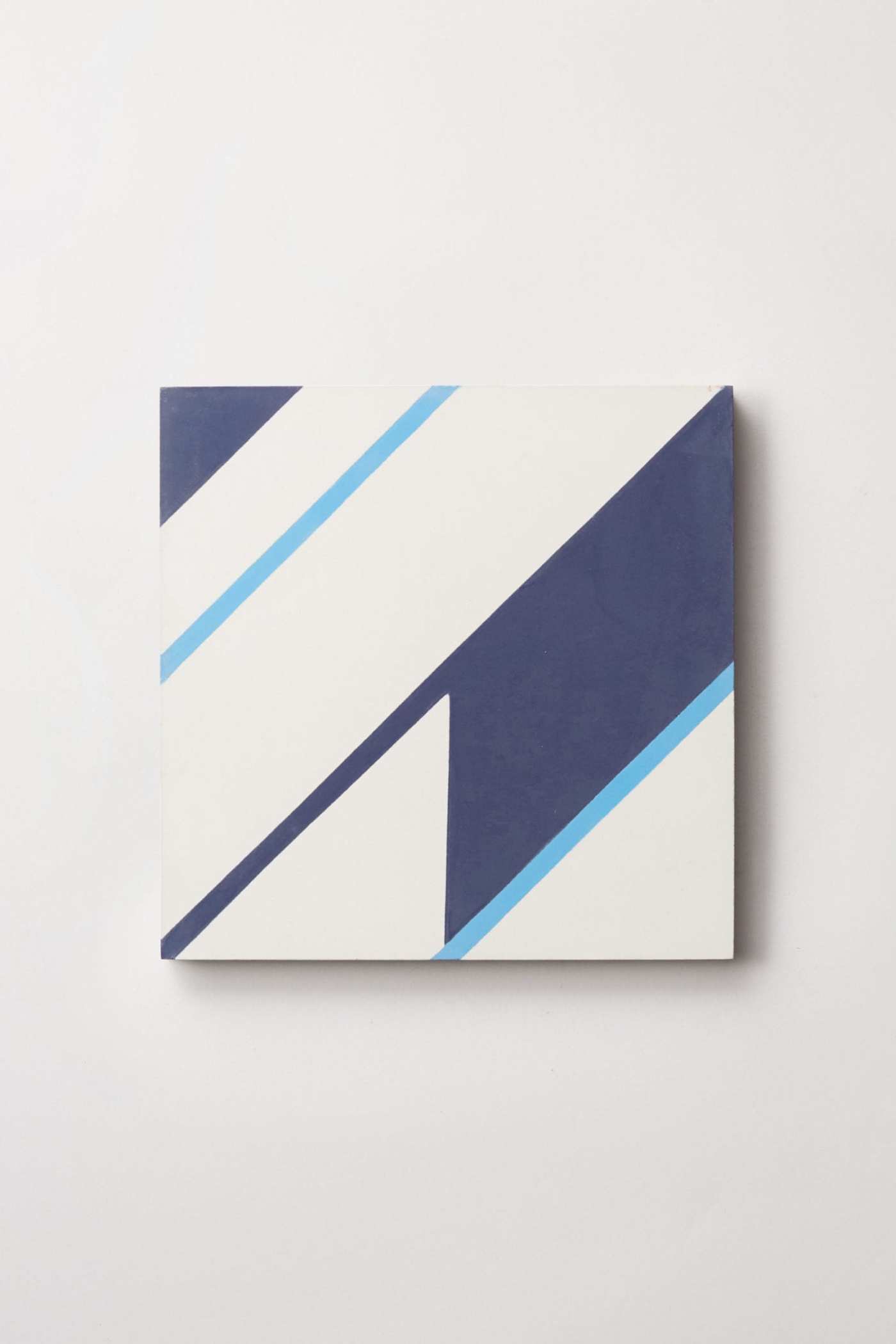 a blue and white tile with a geometric design on a white surface.