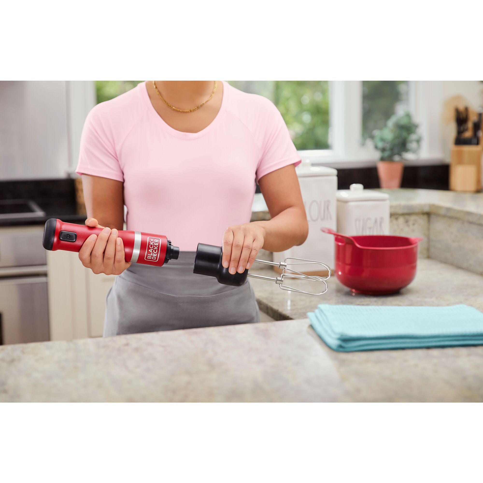 Model showing how to attach the BLACK+DECKER kitchen wand hand mixer attachment to the red power unit