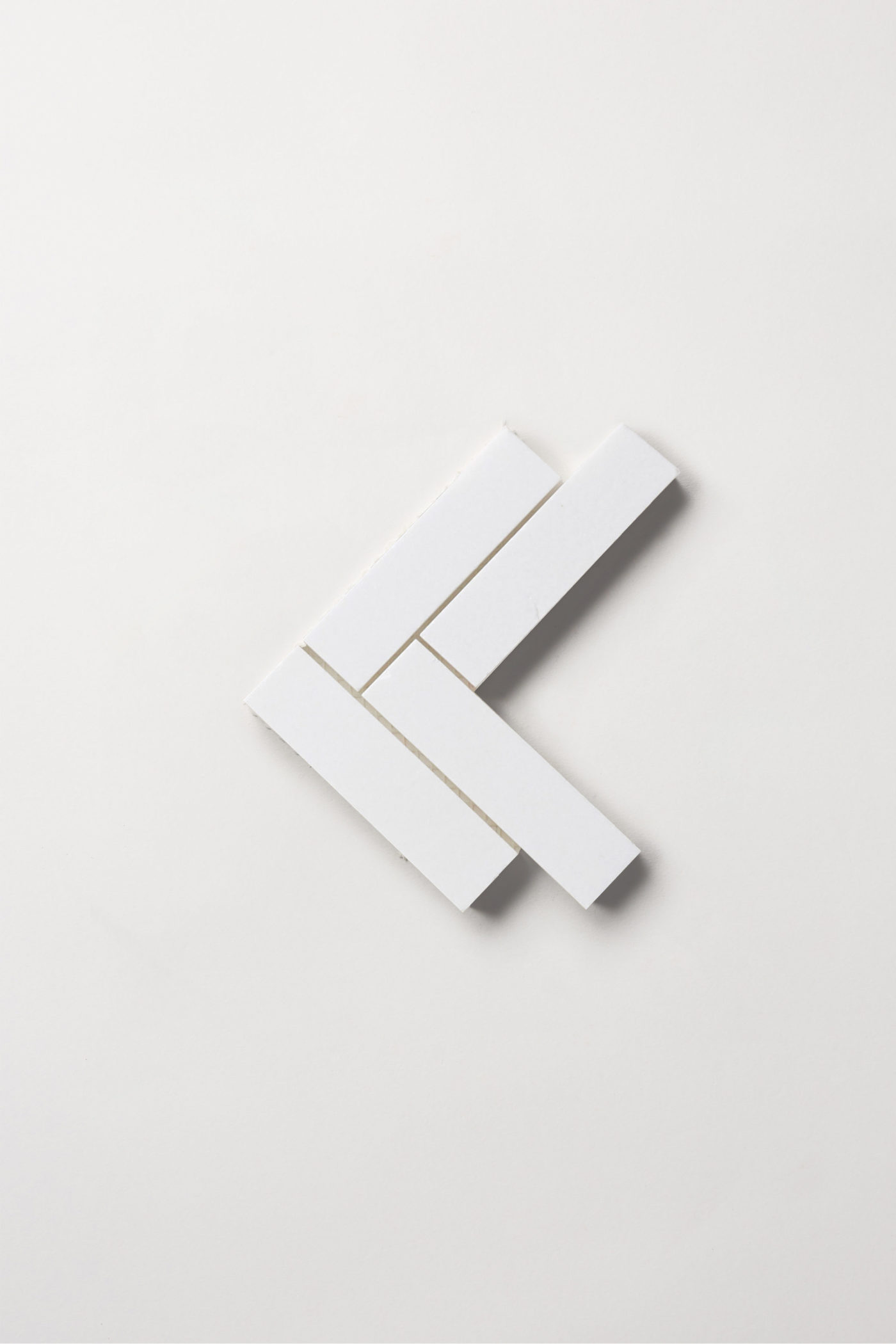 four white rectangular tiles in a chevron pattern on a white surface.