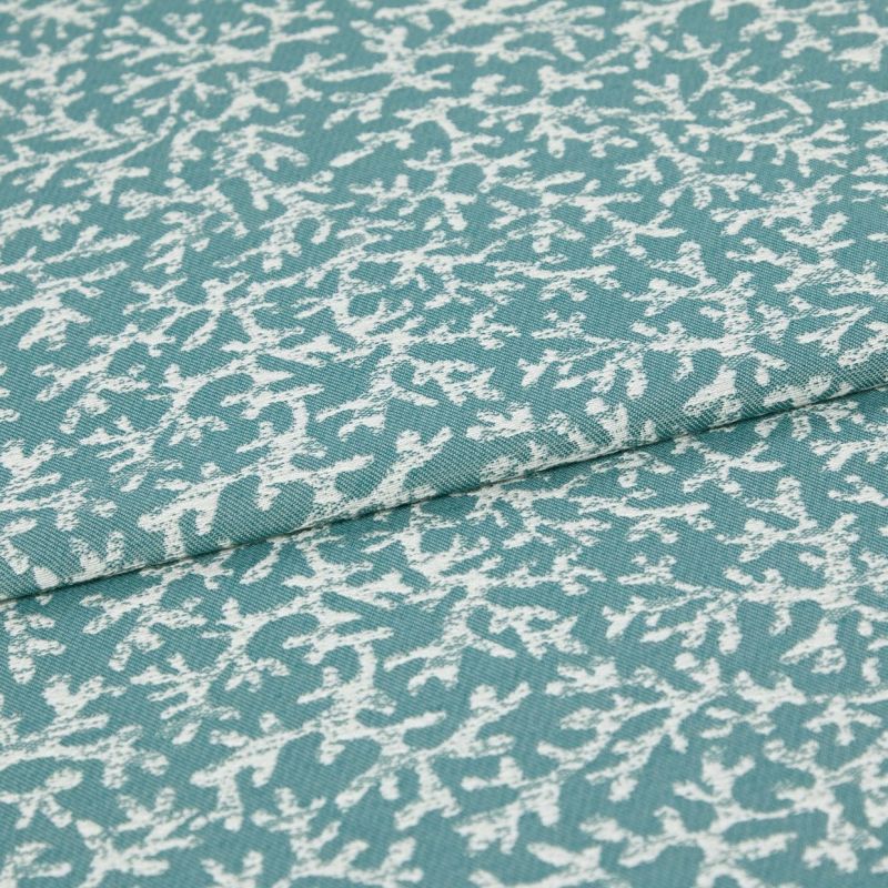 Woven teal upholstery fabric with irregular white abstract print; folded along a seam, lying flat; close-up studio view showing texture and weave.