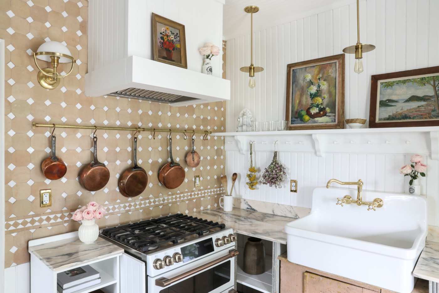 a kitchen with a stove, sink and pictures and pots hanging on the wall.