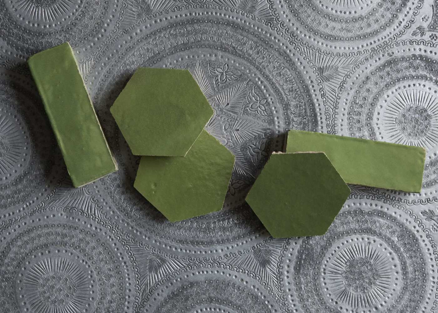 a set of green  tiles on a silver patterned table.