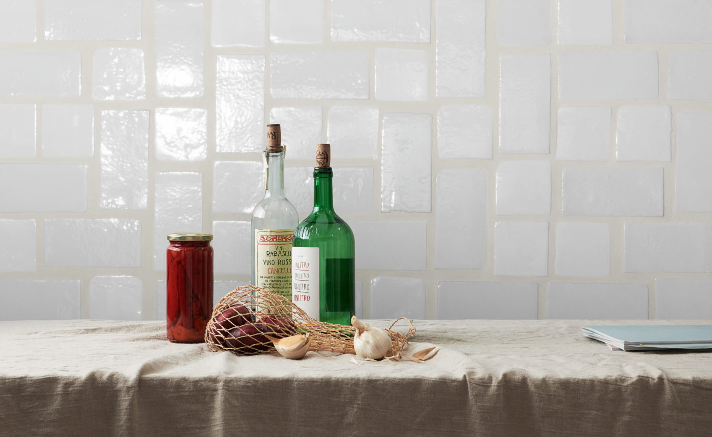 a table with bottles in front of a white tile wall.