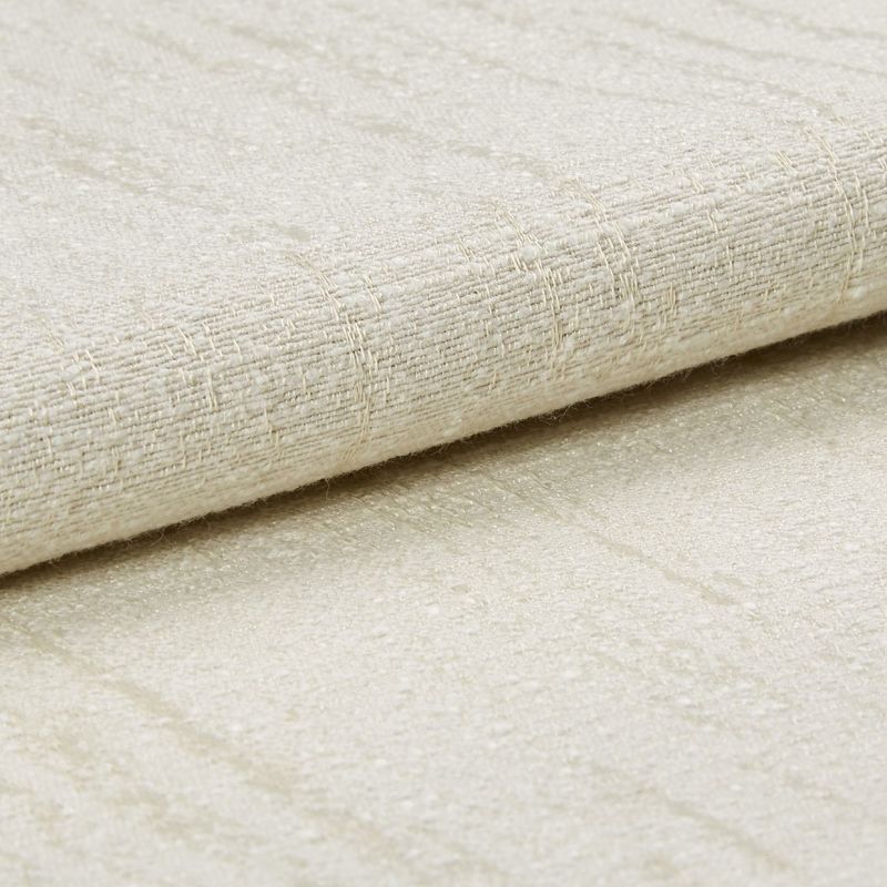 A folded beige woven fabric with subtle sheen and raised grid texture, layered over matching fabric; close-up studio view with soft, diffuse lighting on a neutral surface.