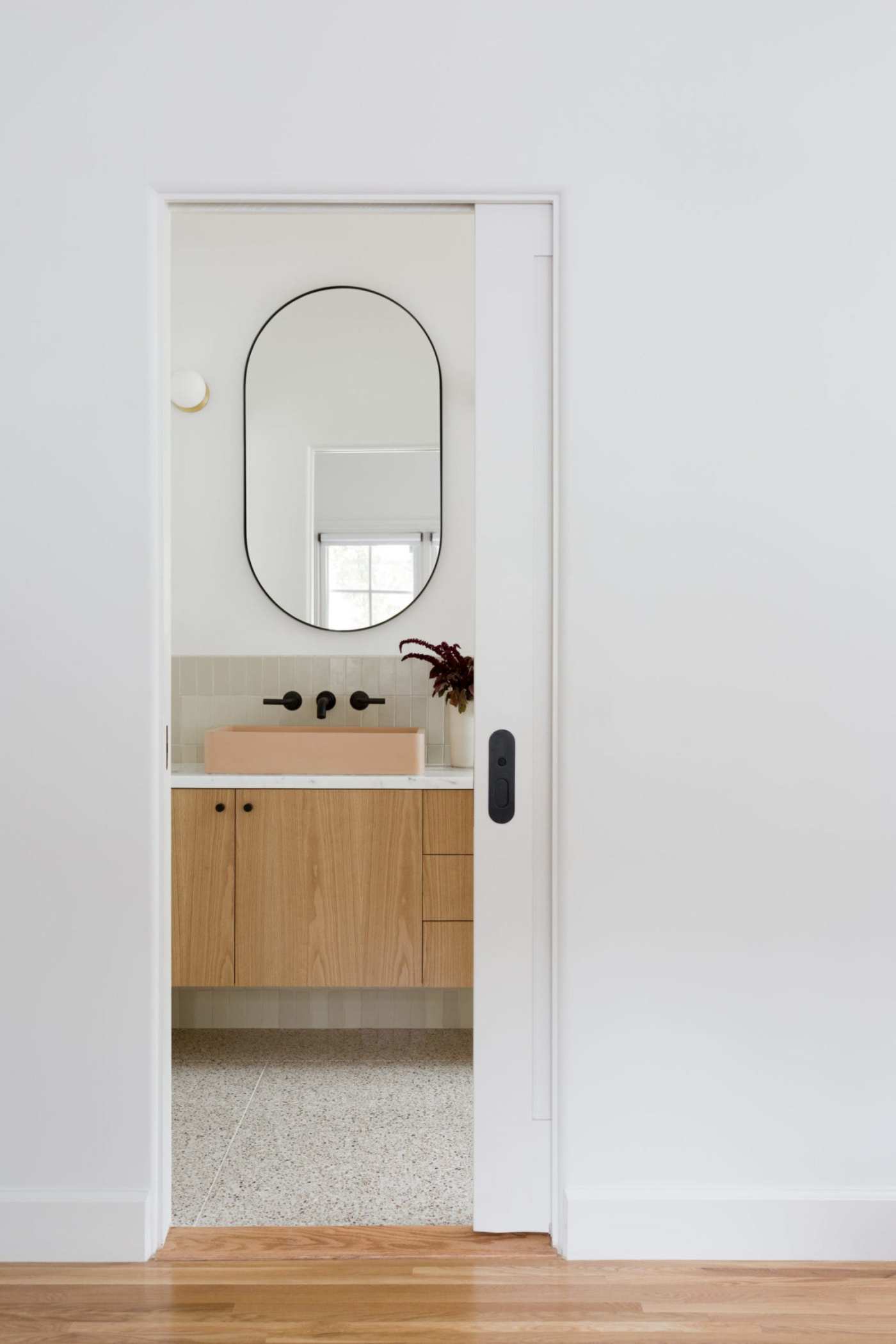 a white bathroom with a wooden floor and a mirror.